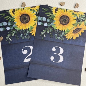 Bruiloft tafelnummer naam set nummers 1 tot en met 10 plus bovenste tafel zonnebloemen op rustiek donkerblauw hout Mirasol kan gepersonaliseerd worden