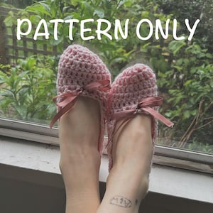 May include: A pair of pink crocheted slippers with a bow on each. The slippers are worn on a person's feet.