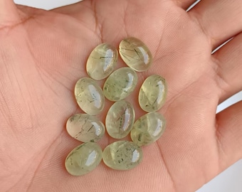 May include: A collection of oval-shaped green aventurine gemstones with black inclusions. The stones are smooth and polished.