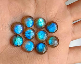 Op de afbeelding: Een verzameling van tien ronde, iriserende labradorit edelstenen. De stenen zijn een mix van blauwe, groene en gouden kleuren.