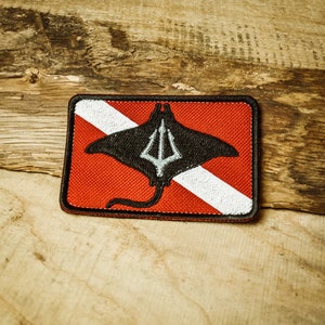 Peut inclure: Un patch de drapeau de plongée sous-marine rouge et blanc avec une silhouette de raie noire et un design de trident.
