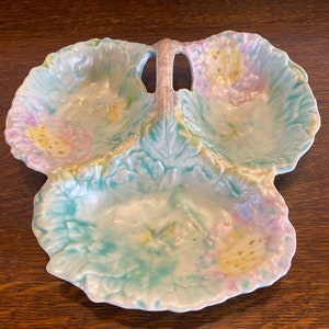 May include: A vintage three-section serving dish with a handle. The dish is made of white ceramic with a light blue glaze and floral designs in shades of pink, yellow, and green.
