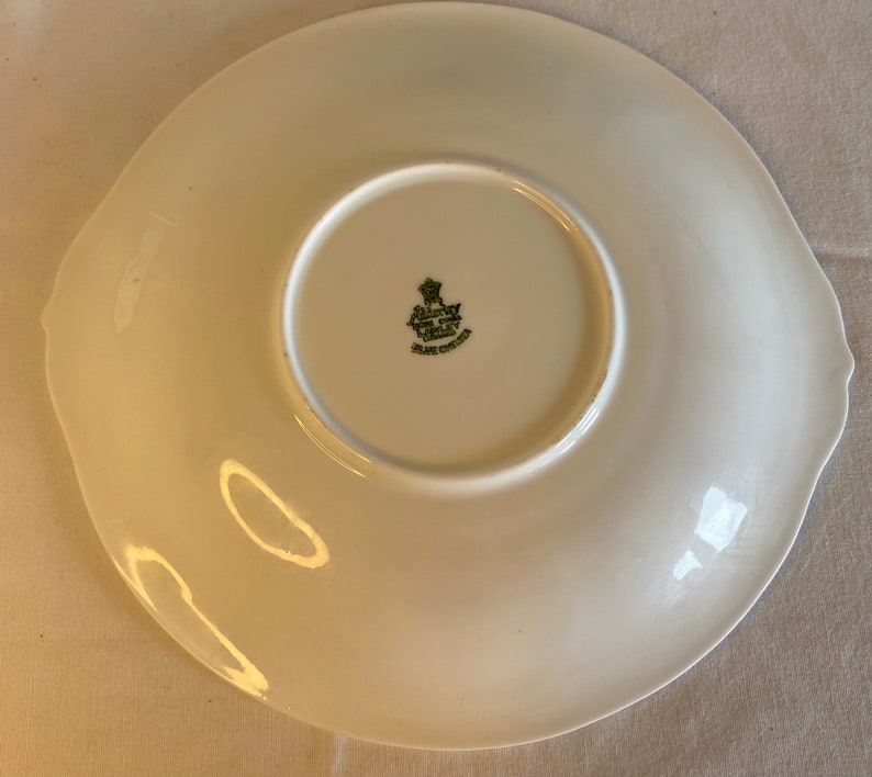 May include: White ceramic plate with a green and gold logo that reads "Royal Crown China Made in England".