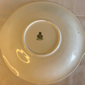 May include: White ceramic plate with a scalloped edge and a green and black logo that reads "Country Life Blue of Chelsea" in the center.