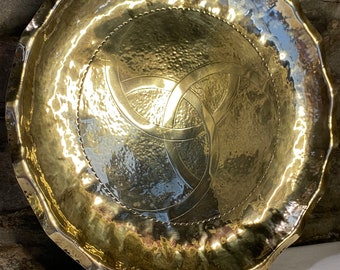 May include: A large, round, brass tray with a hammered finish and a Celtic knot design. The tray has a scalloped edge.