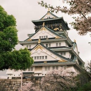 Puede incluir: Un castillo japon&eacute;s blanco y verde con detalles dorados. El castillo est&aacute; rodeado de &aacute;rboles y flores.