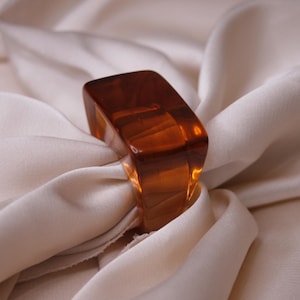 Puede incluir: Un anillo grande de vidrio ámbar con una superficie lisa y pulida.