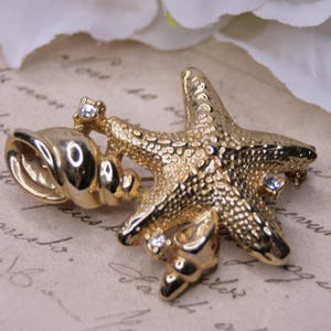 Vintage gold tone starfish and shell brooch with rhinestone