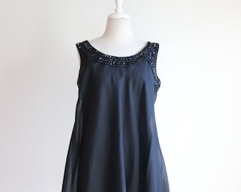May include: A black sleeveless dress with a beaded neckline. The dress is made of a sheer fabric and has a flowing silhouette.