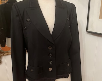 May include: A black blazer with a cropped hem and decorative stitching. The blazer has a v-neck, long sleeves, and four buttons down the front.