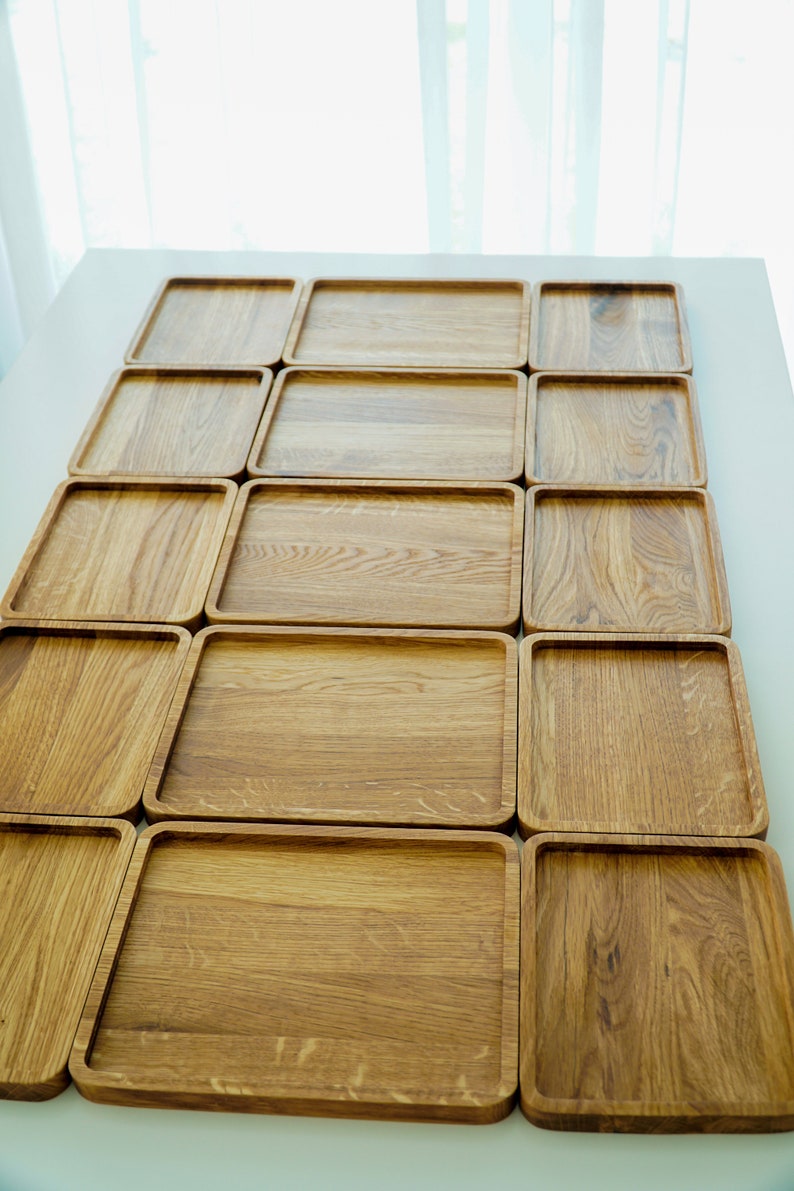 May include: A set of 15 wooden serving trays arranged in a grid pattern. The trays are made of light brown wood and have a smooth, polished finish.