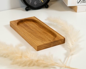May include: A rectangular wooden tray with a rounded oval-shaped depression in the center. The tray is made of light brown wood with a natural grain pattern.