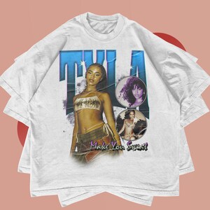 May include: White t-shirt with a graphic print of a woman with the text "T.I.A. Make You Sweat!"