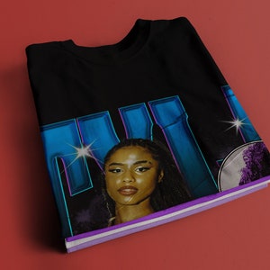 May include: Black t-shirt with a graphic print of a woman's face with blue and purple accents. The text "MILK" is printed in large blue letters.