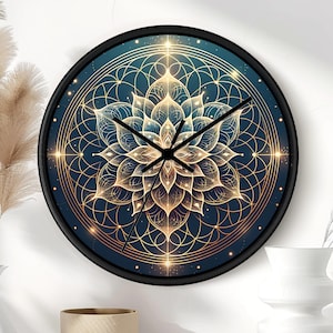 Op de afbeelding: Een ronde wandklok met een zwarte rand, een donkerblauwe wijzerplaat en een goudkleurig geometrisch lotusbloempatroon. De klok heeft drie zwarte wijzers en toont een symmetrisch, ingewikkeld ontwerp met stralende lijnen en kleine stervormige punten.