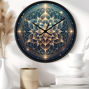 Puede incluir: Reloj de pared redondo con marco negro. La esfera del reloj presenta un diseño de flor de loto dorada y verde azulado con patrones geométricos. Las manecillas del reloj son negras. El reloj se muestra en una pared blanca.