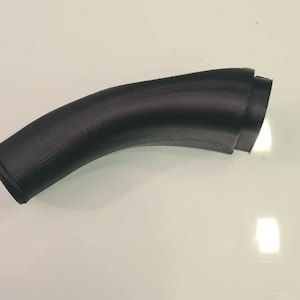 May include: A black, curved pipe with a textured surface. The pipe has a gradual bend and a flared end. The object is likely a component or part of a larger system.