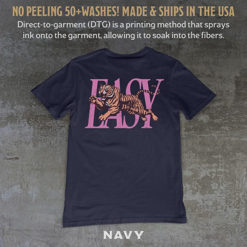 May include: Navy blue t-shirt with a pink tiger graphic and the text "EASY LADY". The shirt is made with a direct-to-garment printing method. The text "NAVY" is at the bottom of the shirt.