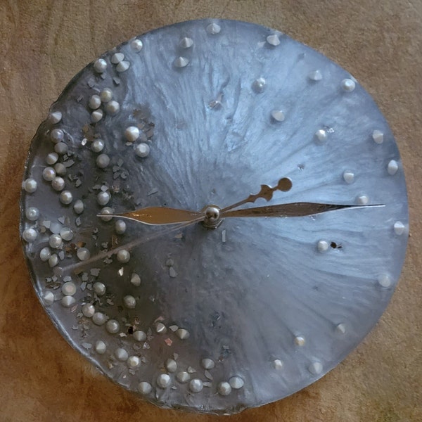 Solid resin clock. Silver with pearl-like stones, and mirror chips. 10-inch round can be hung or on an easel. Great one-of-a-kind gift idea.