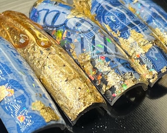 May include: Five blue and gold nail tips with a dollar bill design. The tips are curved and have a glossy finish.