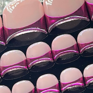 May include: A set of press-on nails featuring a nude base with a metallic magenta chrome tip. The nails have a rounded square shape and a glossy finish, with a white lace-like pattern printed on the upper portion of the nude base area.