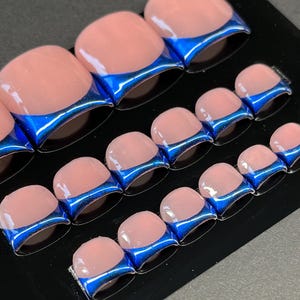 May include: A set of press-on toenails with a light pink base and a vibrant blue metallic French tip. The nails are arranged in rows on a black surface, showcasing a modern and stylish design. The glossy finish adds to their appeal.