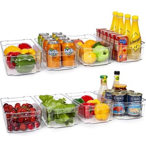 May include: Clear plastic refrigerator storage bins filled with various food items, including fruit, vegetables, canned goods, and beverages. The bins are stacked in two rows, with the top row containing a variety of fruits and vegetables, and the bottom row containing canned goods and beverages.