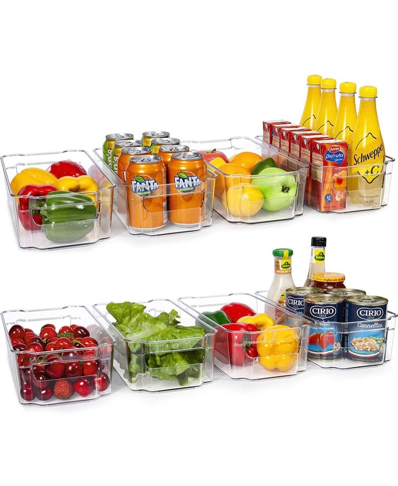 May include: Clear plastic refrigerator storage bins filled with various food items, including fruit, vegetables, canned goods, and beverages. The bins are stacked in two rows, with the top row containing a variety of fruits and vegetables, and the bottom row containing canned goods and beverages.