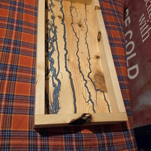 May include: A rectangular wooden tray featuring a light tan natural wood grain finish with prominent knots and intricate, branching blue fractal patterns burned into the surface. The tray has raised sides and a smooth, light-colored wood texture.