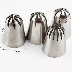 May include: Four stainless steel piping tips with different decorative designs. The tips are 5 cm tall and 3.5 cm wide.