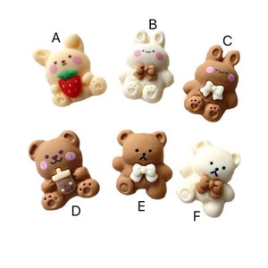 May include: Six adorable resin charms featuring a variety of animal designs. The charms include a brown bear holding a boba tea, a brown bear with a bow, a white bear with a bow, a white bunny with a bow, a brown bunny with a bow, and a white bunny holding a strawberry.