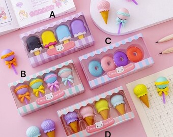 May include: Assortment of colorful eraser sets featuring various sweet treats, including ice cream cones, lollipops, and donuts. Each set is packaged in a clear plastic box with a pink and white striped design. The boxes are labeled with the text "Dear Cake Shop".