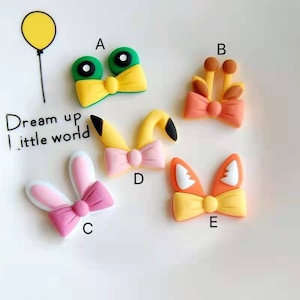 Puede incluir: Cinco pinzas para el pelo de fieltro de colores con diferentes diseños de animales. Los lazos son amarillos, rosas, naranjas y rojos. Los diseños de animales incluyen una rana, una jirafa, un conejito, un Pikachu y un zorro.