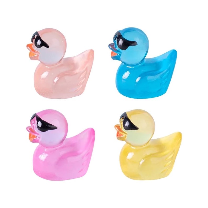 May include: Four rubber duck toys with sunglasses. The ducks are pink, blue, yellow, and light pink. Each duck has a different color of sunglasses.