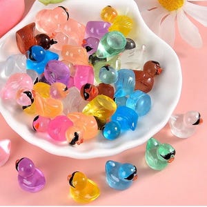 May include: A bowl filled with colorful, translucent plastic bird figurines. The birds are in various poses and colors, including pink, blue, green, yellow, and orange.