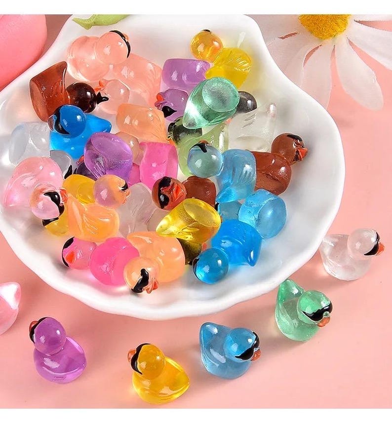 May include: A bowl filled with colorful, translucent plastic bird figurines. The birds are in various poses and colors, including pink, blue, green, yellow, and orange.
