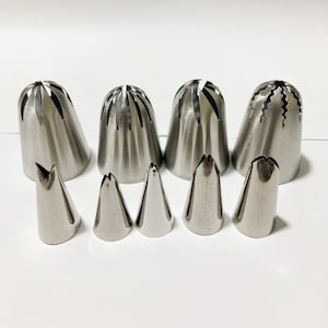 May include: Set of 8 stainless steel piping tips for decorating cakes and cupcakes. The set includes 5 large tips with different decorative patterns and 3 smaller tips with pointed ends.