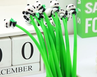 May include: A bunch of green panda pens with black and white panda heads. The pens are in a white ceramic pot. The pot is sitting on a white wooden calendar that says "December 0".