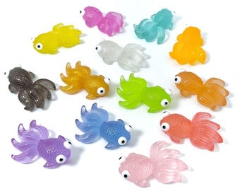 May include: A set of 12 colourful, translucent goldfish figurines with googly eyes. The figurines are made of plastic and are about 5 cm long. They are perfect for adding a touch of whimsy to any room.