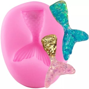 Puede incluir: Molde de silicona rosa con un diseño de cola de sirena. Se muestran tres colas de sirena en el molde, una es azul, una es rosa y una es dorada.