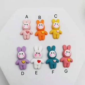 Peut inclure: Sept embellissements en résine en forme de lapin de différentes couleurs avec un motif en forme de cœur. Les lapins sont rose, orange, jaune, violet, blanc, bleu sarcelle et corail.