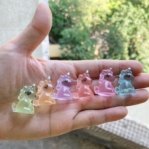 Könnte beinhalten: Sechs kleine Einhorn-Figuren aus klarem Kunststoff mit einem Pastellfarbverlauf. Die Einhörner sind in einer Reihe von links nach rechts angeordnet, beginnend mit einem hellgrünen Einhorn und endend mit einem hellblauen Einhorn. Die Einhörner sind alle in die gleiche Richtung ausgerichtet und haben geschlossene Augen.