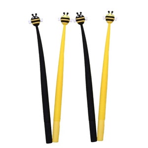 May include: Three pens with bee-shaped toppers. One pen is black and the other two are yellow.