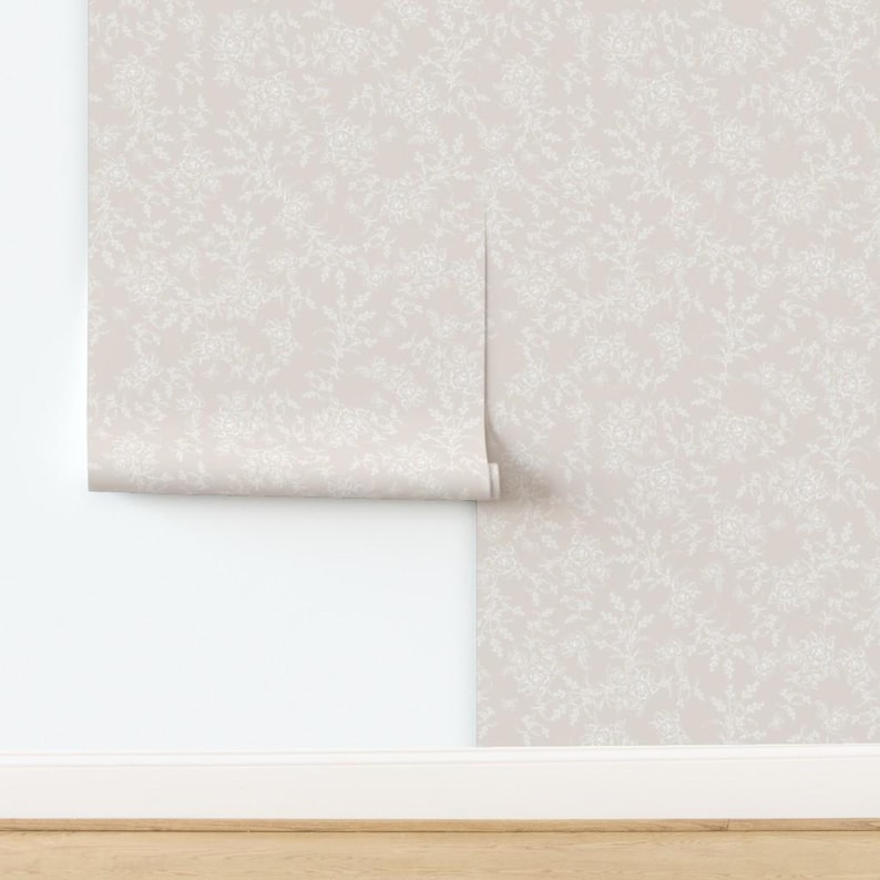 Puede incluir: Un rollo de papel tapiz de color rosa p&aacute;lido con un delicado patr&oacute;n floral blanco. El papel tapiz est&aacute; parcialmente desenrollado, revelando el patr&oacute;n.