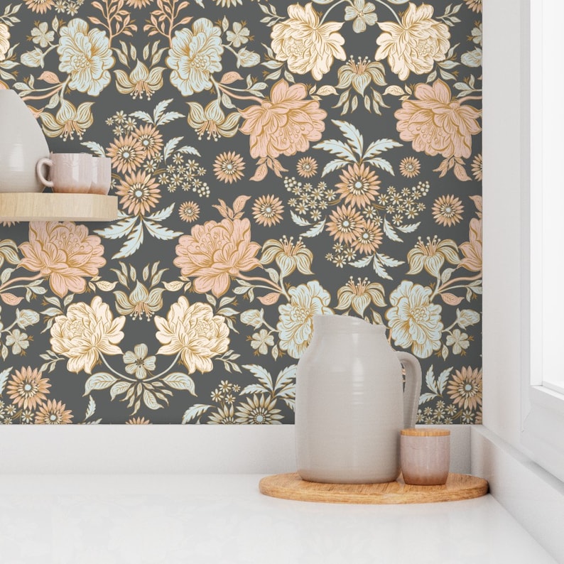 May include: Wallpaper featuring a dark gray background with a repeating floral pattern in shades of peach, cream, and pale blue. The design includes large blossoms, smaller daisy-like flowers, and leafy stems arranged in a symmetrical botanical layout.