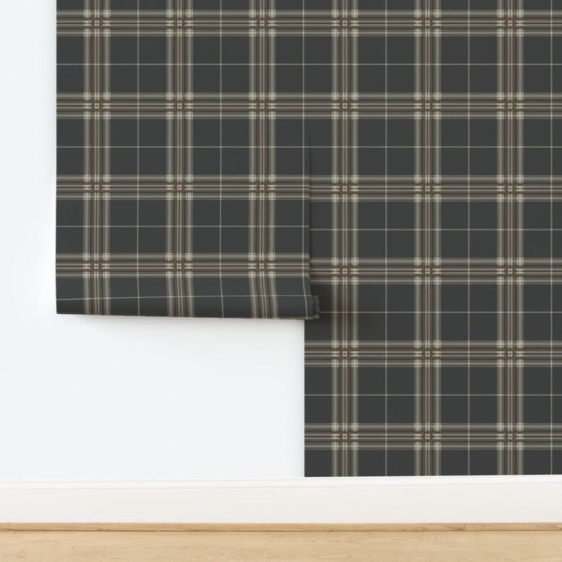 Op de afbeelding: Een rol zwart-wit geruite behang met een bruine accentkleur. Het behang is gedeeltelijk uitgerold op een witte muur.