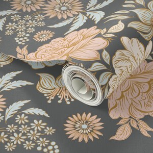 May include: A roll of wallpaper featuring a dark gray background with a repeating floral pattern. The design includes large, stylized flowers in shades of soft pink and muted gold, accented by light blue leaves and small white flower clusters.