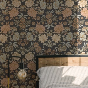 May include: Wallpaper featuring a dark charcoal background with a repeating floral pattern in muted shades of peach, light blue, and cream. The design includes various blossoms, leaves, and stems arranged in a dense, symmetrical botanical layout.