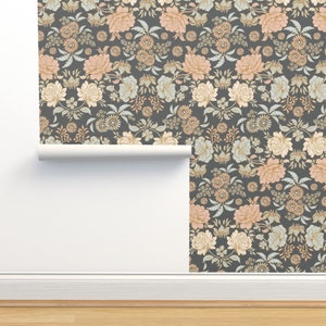 May include: A roll of wallpaper featuring a dark charcoal gray background with a repeating floral pattern. The design includes large peach-colored roses, smaller light blue blossoms, and intricate green foliage arranged in a dense, symmetrical layout.