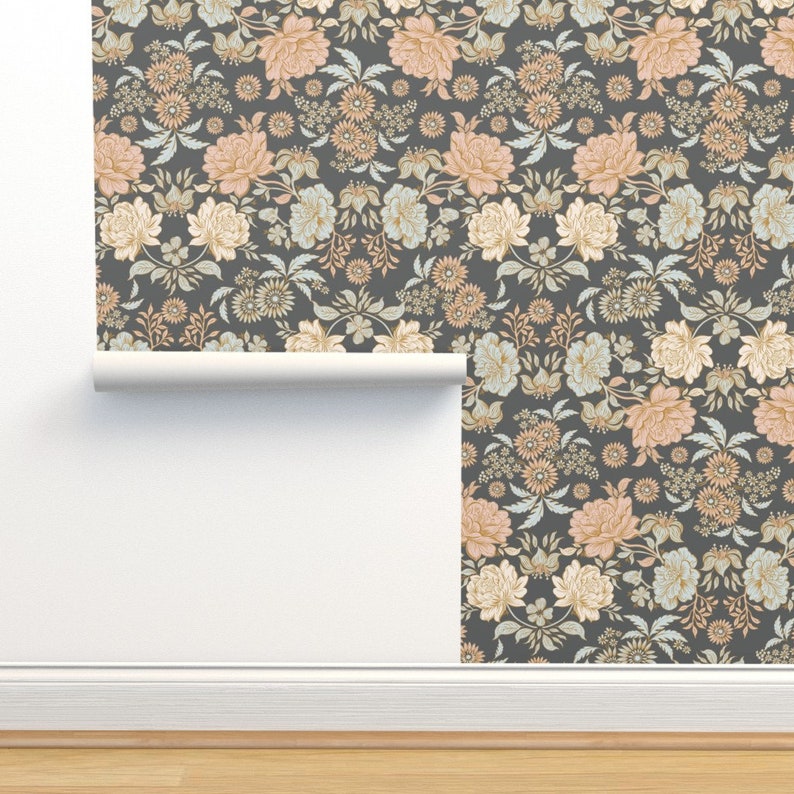May include: A roll of wallpaper featuring a dark charcoal gray background with a repeating floral pattern. The design includes large peach-colored roses, smaller light blue blossoms, and intricate green foliage arranged in a dense, symmetrical layout.